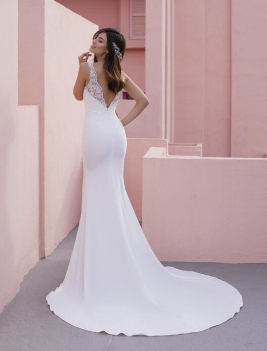 Bruidsjurk Pronovias: Coneflower. Mouwloze trouwjurk van crêpe met V-hals. Een verfijnde, elegante look van pure crêpe en een fijne kanten bovenlaag op het lijfje. Met een mooie V-rug en vloeiende kapelsleep die gracieus beweegt. Kom jij deze bruidsjurk passen in onze bruidswinkel?