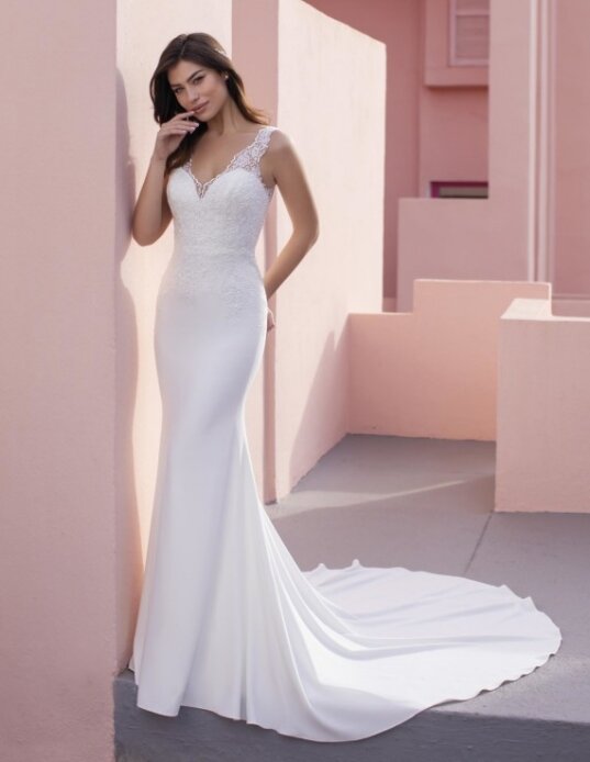 Bruidsjurk Pronovias: Coneflower. Mouwloze trouwjurk van crêpe met V-hals. Een verfijnde, elegante look van pure crêpe en een fijne kanten bovenlaag op het lijfje. Met een mooie V-rug en vloeiende kapelsleep die gracieus beweegt. Kom jij deze bruidsjurk passen in onze bruidswinkel?
